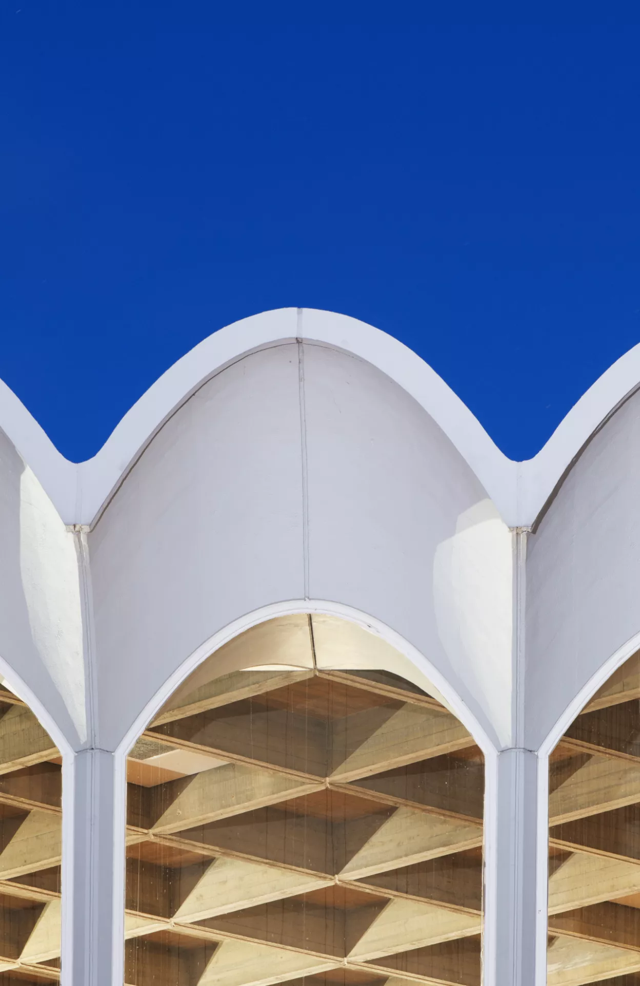 Newly listed at Grade II: The Central Hall, Fitzwilliam College, Cambridge Fitzwilliam College, Storeys Way, Cambridge, Cambridgeshire.  Detail view of west elevation to lantern of central hall, lit at twilight, showing arched glazing with parabolic hoods, designed by Denys Lasdun, built 1960-63. View from west. © Historic England Archive