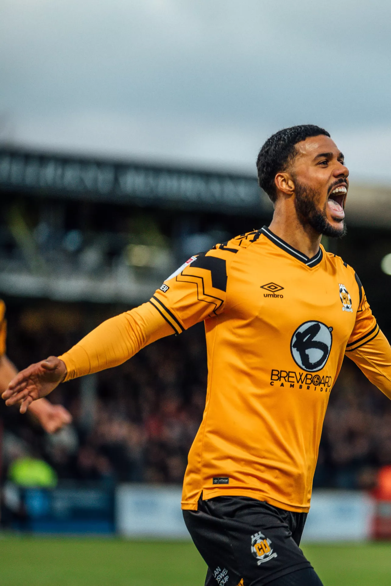 Player in a yellow Cambridge Utd shirt celebrates a goal