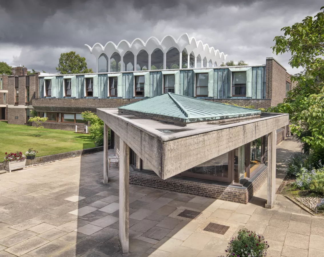 Newly listed at Grade II: The Central Hall, Fitzwilliam College, Cambridge Fitzwilliam College, Storeys Way, Cambridge, Cambridgeshire.  General view of west elevation to central hall with projecting former senior common room (SCR) and its copper clad concrete roof, designed by Denys Lasdun, built 1960-63. View from south west. © Historic England Archive